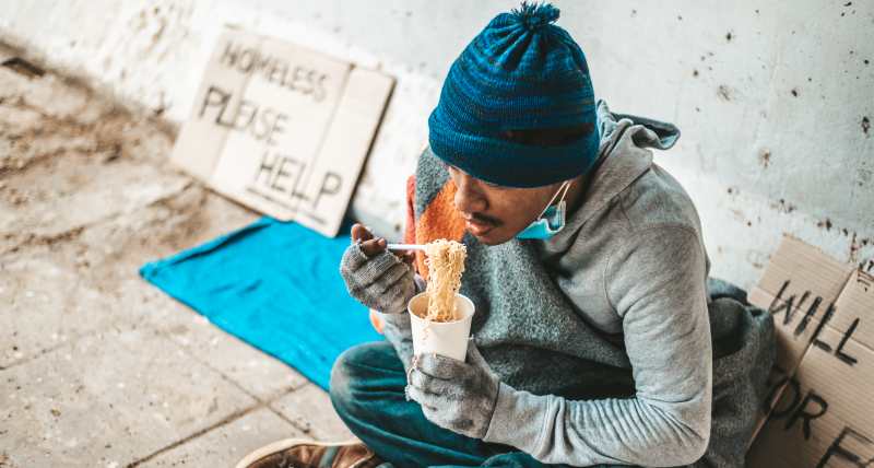 the beggars sat wrapped in cloths and eating noodles.